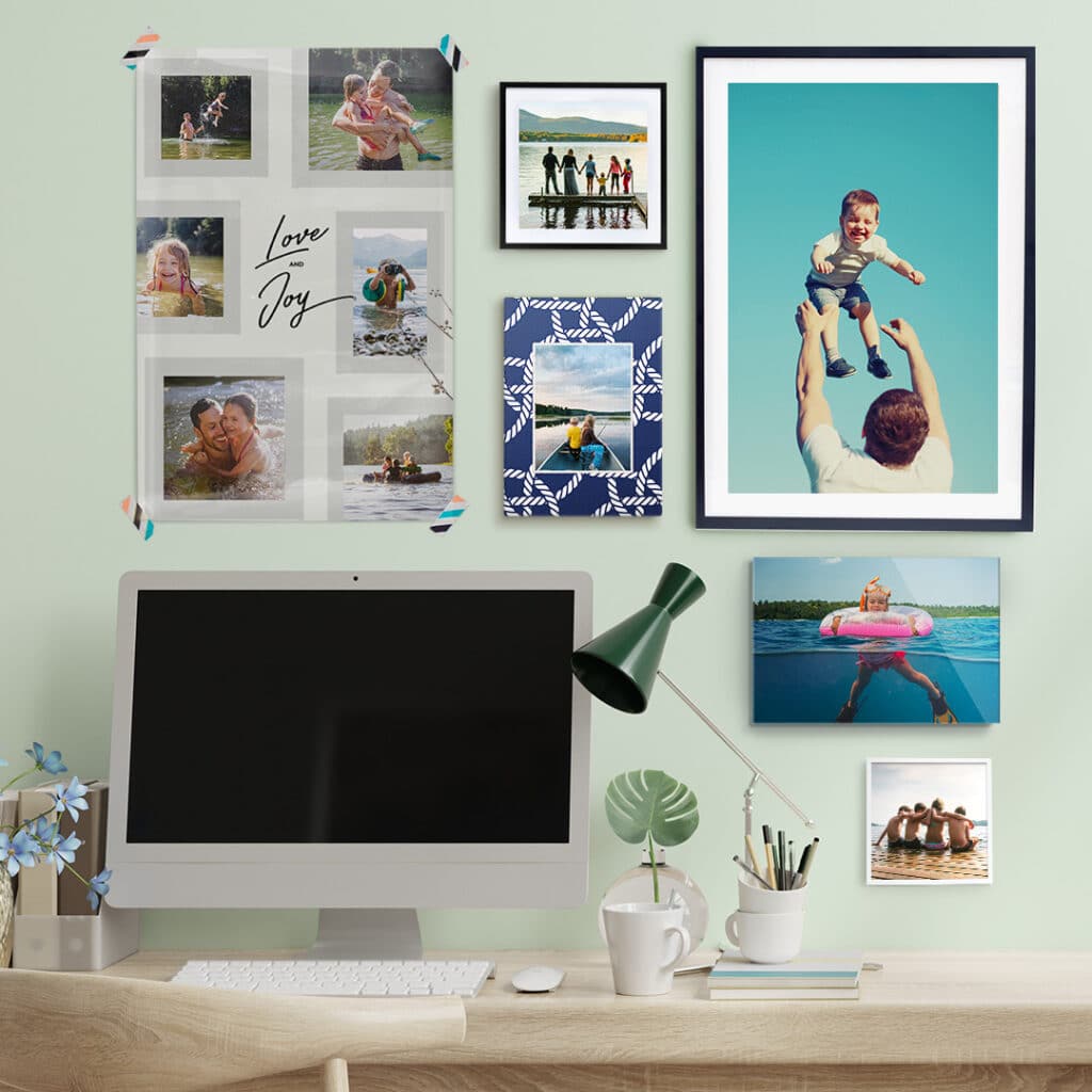 A computer desk in front of a wall with lots of wall art with family photos.