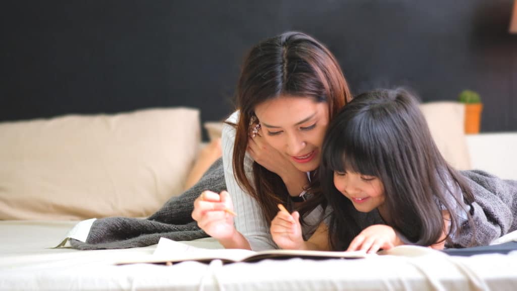 Mother and daughter writing together in bedroom 